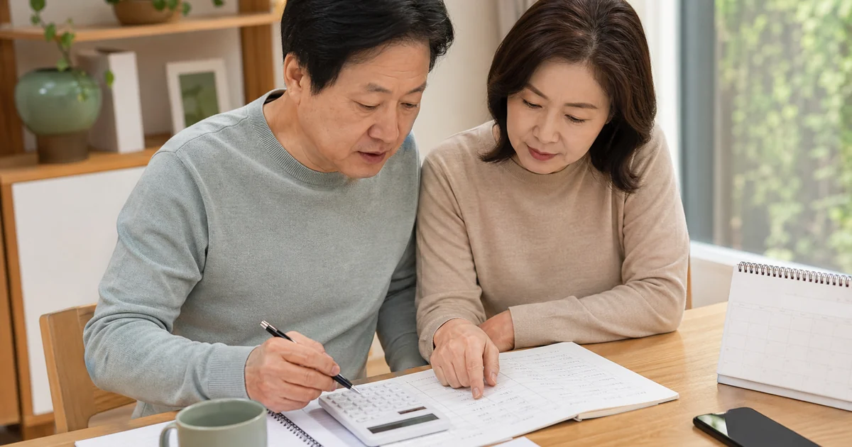 정기예금 기간과 금리 조건을 계산기로 비교하는 중년 부부
