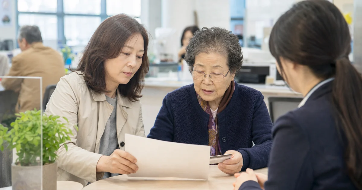 행정복지센터에서 어머니의 기초연금 신청 시기를 상담하는 중년 딸