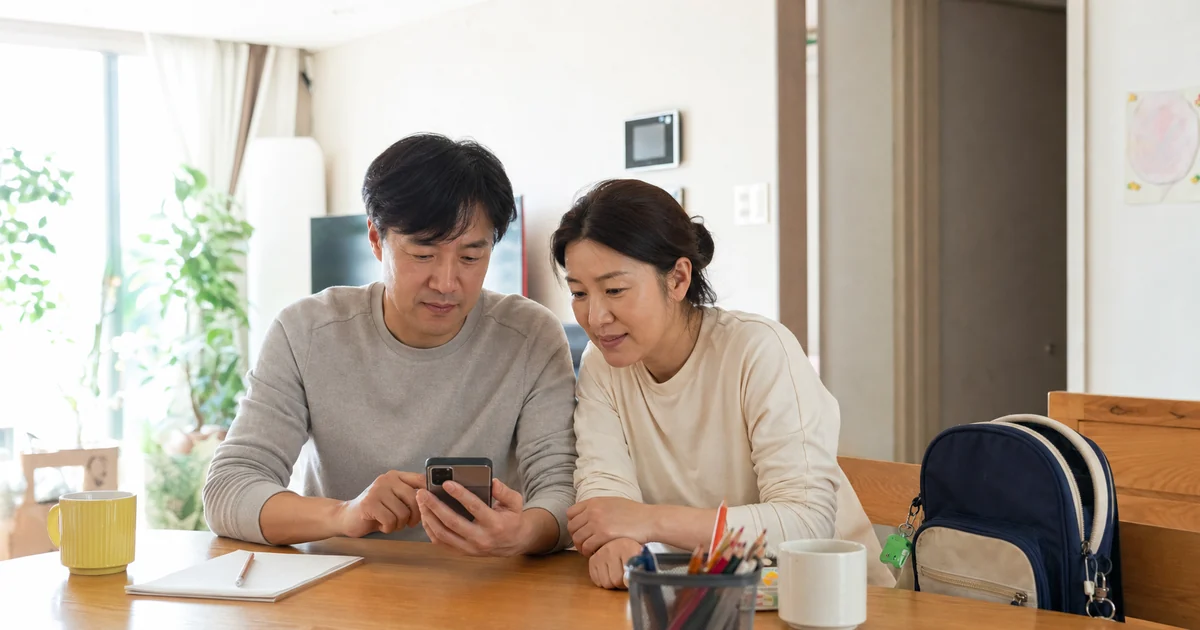 자녀의 아동수당 대상 여부를 스마트폰으로 확인하는 40대 부부